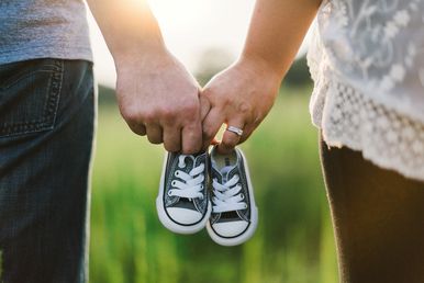 Paar Hand in Hand mit Babyschuhen